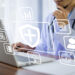 A person in a lab coat, possibly a doctor, works on a laptop. Overlay icons indicate healthcare and technology elements such as a shield with a cross, a profile, a document, gears, and a light bulb, suggesting health informatics or telemedicine as well as software solutions for general insurance. | MONEY6X