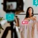 A woman holding clothes on hangers stands in front of a camera on a tripod, surrounded by social media and e-commerce icons like a shopping cart, dollar sign, heart with 25 likes, house, and chat bubble with 9 messages. A plant is visible in the background as she shares tips to make money fast. | MONEY6X