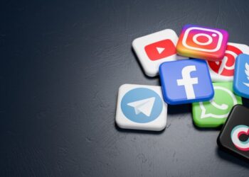 A dark surface is scattered with various social media application icons, including YouTube, Instagram, Pinterest, WhatsApp, Facebook, Twitter, Telegram, and TikTok. The colorful icons create a contrast against the minimalistic background—highlighting some of the best social media to make money. | MONEY6X