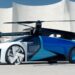 A sleek futuristic blue and white flying car with four large propellers on top, parked in front of a modern white building with curved architectural elements. Investors eyeing flying car stocks are excited by its streamlined design and large wheels, combining features of both a car and a drone. | MONEY6X