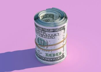 A neatly rolled bundle of U.S. hundred-dollar bills, a symbol of debt management, is secured with a rubber band and positioned upright against a pastel pink background. The roll casts a shadow to the left, adding depth to the image. | MONEY6X
