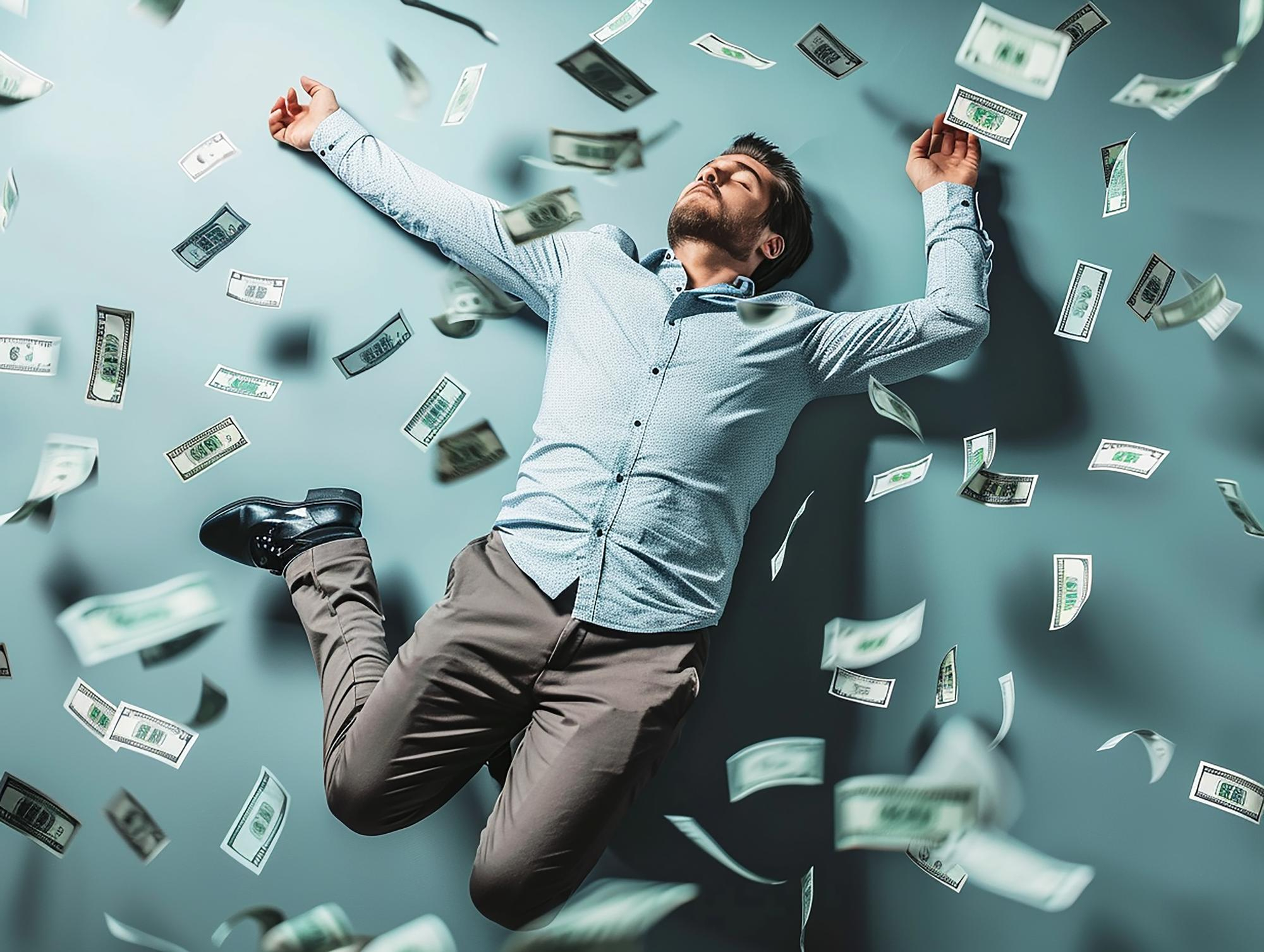 A man dressed in a light blue shirt and gray trousers is lying on the ground with his arms and legs spread out. He appears relaxed and content as dollar bills rain down around him, creating a sense of wealth and abundance, much like the opportunities found on Money6x.com earning. | MONEY6X