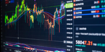 A computer screen displays colorful financial charts and graphs showing fluctuating stock prices, candlestick patterns, trend lines, and trading indicators, with price data and figures on the right side. | MONEY6X
