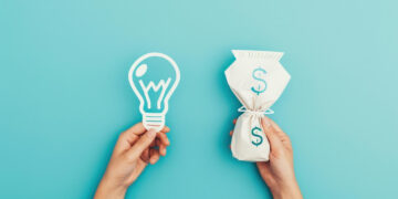 Two hands against a blue background: one holds a paper cut-out of a light bulb, symbolizing ideas, while the other holds a bag with a dollar sign, representing money or passive income. | MONEY6X