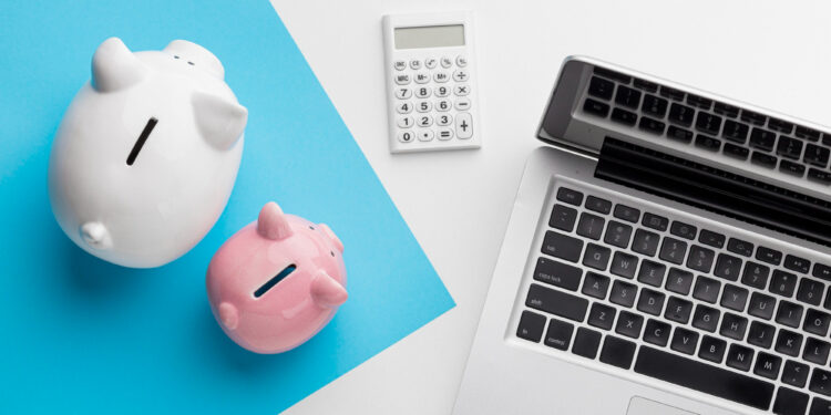 A white and a pink piggy bank, a white calculator, and a silver laptop on a white and blue background, symbolizing savings and financial planning. | MONEY6X