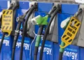 Four gas pumps at a station, with some nozzles covered by yellow “Sorry out of use” signs, indicating they are not available for fueling. The pumps are blue and display the word “synergy.”. | MONEY6X
