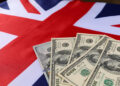 Four U.S. hundred-dollar bills are spread out on top of a British flag. | MONEY6X