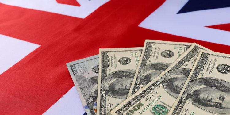 Four U.S. hundred-dollar bills are spread out on top of a British flag. | MONEY6X