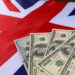 Four U.S. hundred-dollar bills are spread out on top of a British flag. | MONEY6X