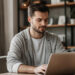 A man working on a laptop at a wooden desk. | MONEY6X